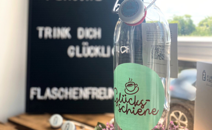 Glastrinkflasche mit Logo des Cafe´s Glücksschiene