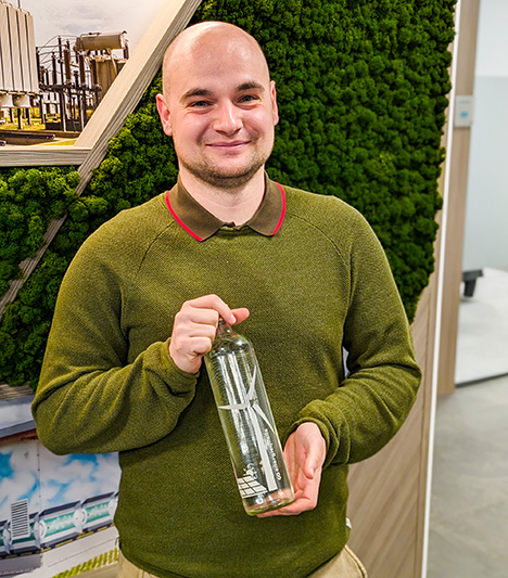 Mitarbeiter der Energiequelle GmbH hält eine Flasche in der Hand