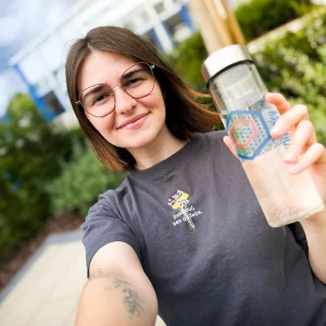 Mitarbeiterin von Prodinger macht ein Selfie und hält die bedruckte Flasche aus Glas in die Kamera