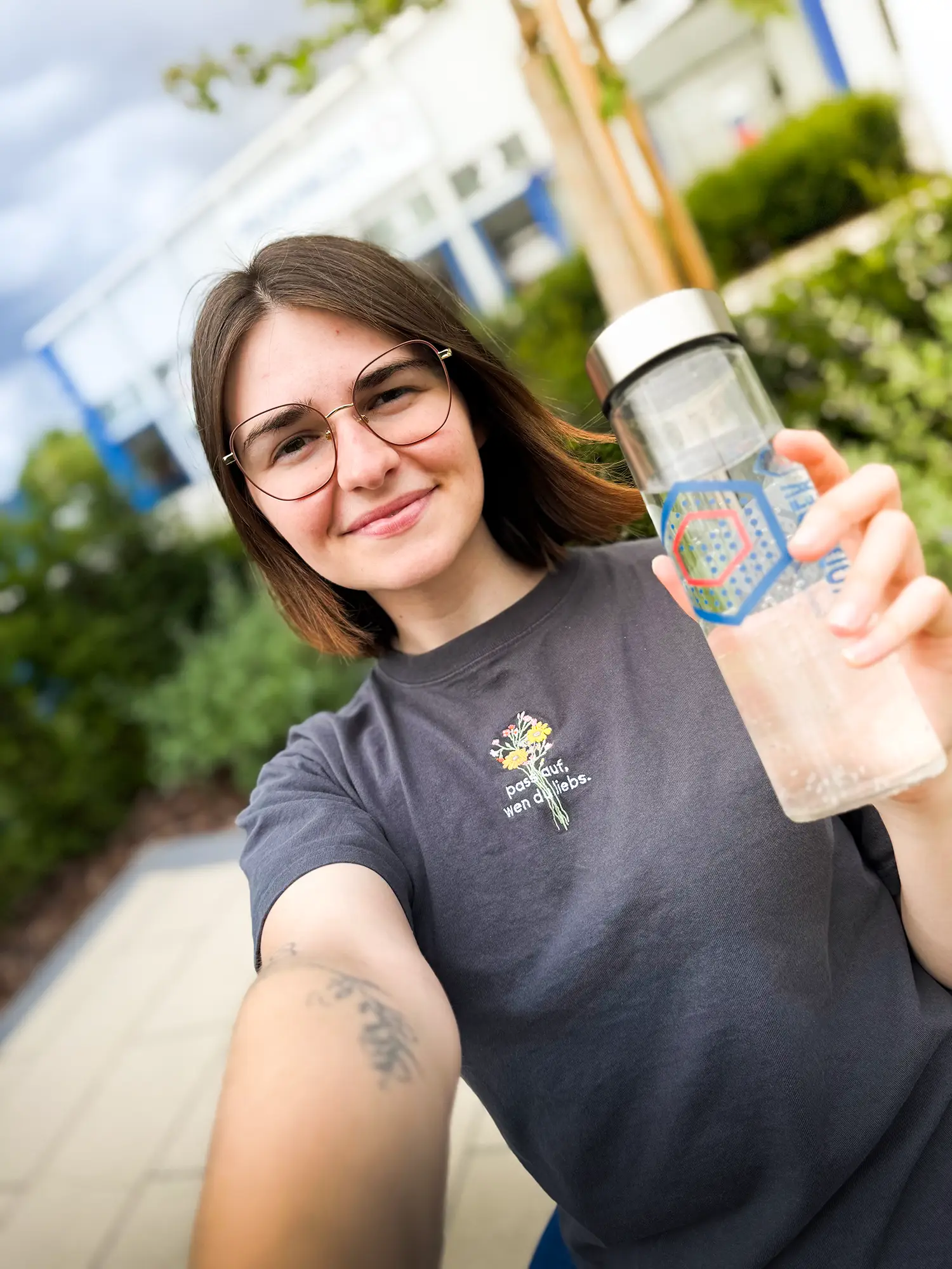 Mitarbeiterin von Prodinger macht ein Selfie und hält die bedruckte Flasche aus Glas in die Kamera