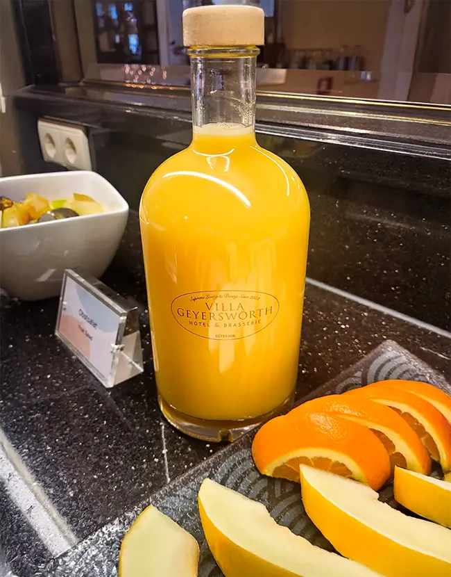 wasserflasche aus glas mit Logo gefüllt mit Orangensaft an einem Frühstücksbuffet