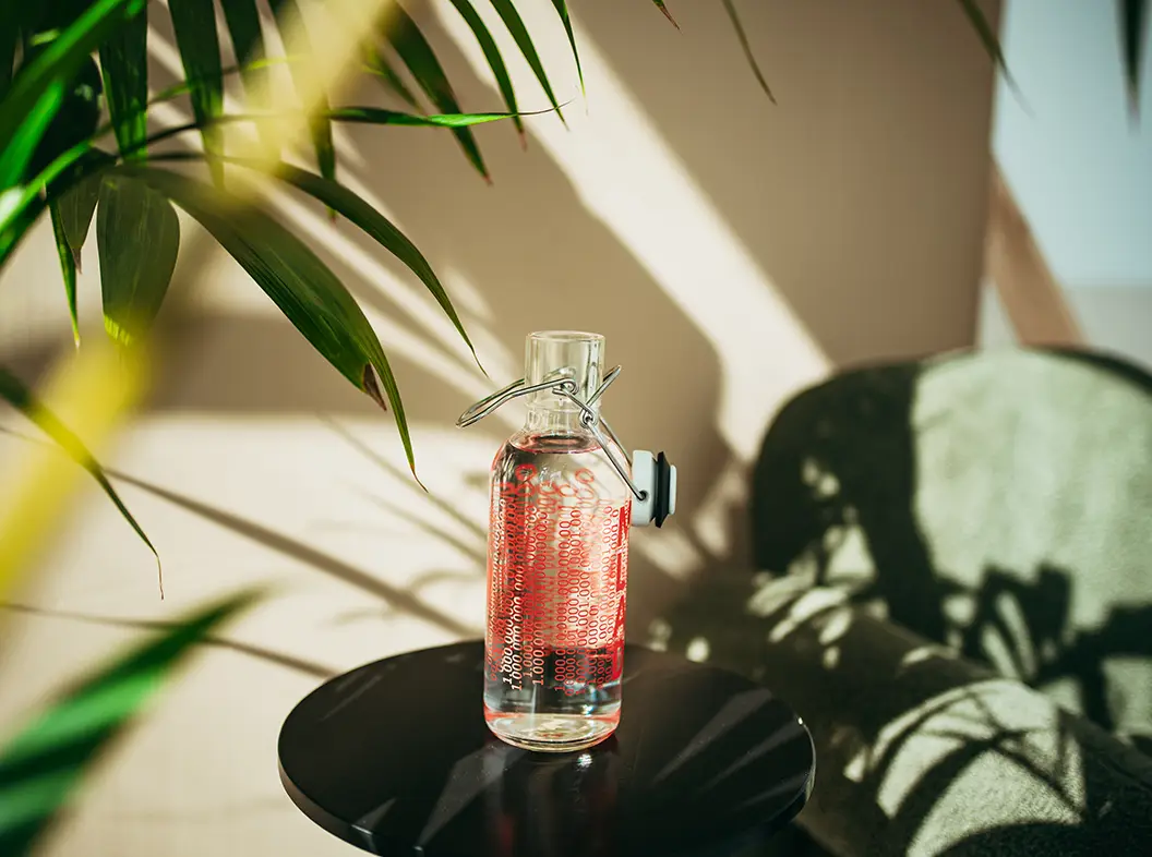 individuell gestaltete Trinkflasche mit Logo und Design auf einem kleinen Tisch neben einem grünen Sessel